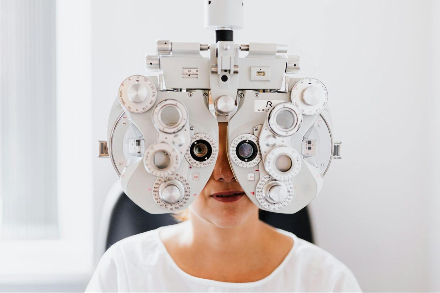 A patient having their vision measured behind a phoropter in the exam room at New Westminster Eye Clinic